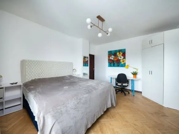 Cozy hotel room in Tallinn featuring a large bed, desk, and vibrant wall art.