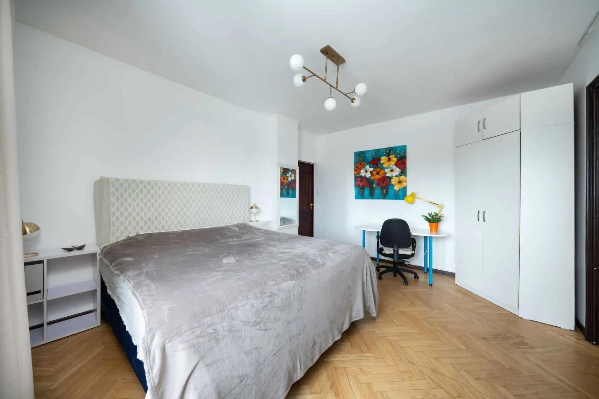 Modern Tallinn hotel room with comfortable bed and workspace. Cozy hotel room in Tallinn featuring a large bed, desk, and vibrant wall art.