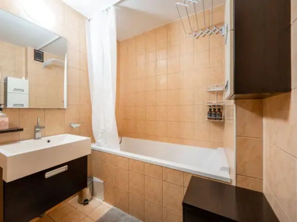 Bright hotel bathroom with bathtub, sink, mirror, and toiletries at Koolrooms Tallinn.