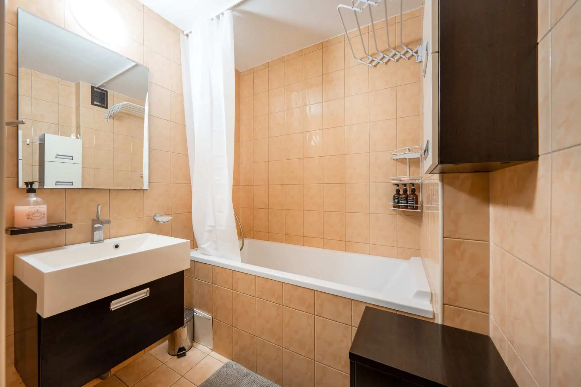 Bright hotel bathroom with bathtub, sink, mirror, and toiletries at Koolrooms Tallinn.