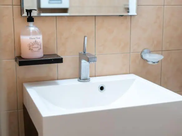 Clean and contemporary hotel bathroom featuring a white sink, modern faucet, and beige wall tiles in Tallinn.