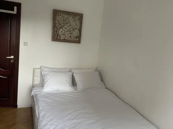 Comfortable white bed with pillows, minimalist decor, and art on the wall at Koolrooms Tallinn.