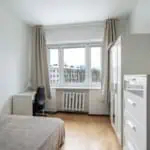 Bright and modern Tallinn apartment featuring a comfortable bed, white furniture, and large windows offering scenic views of the city.