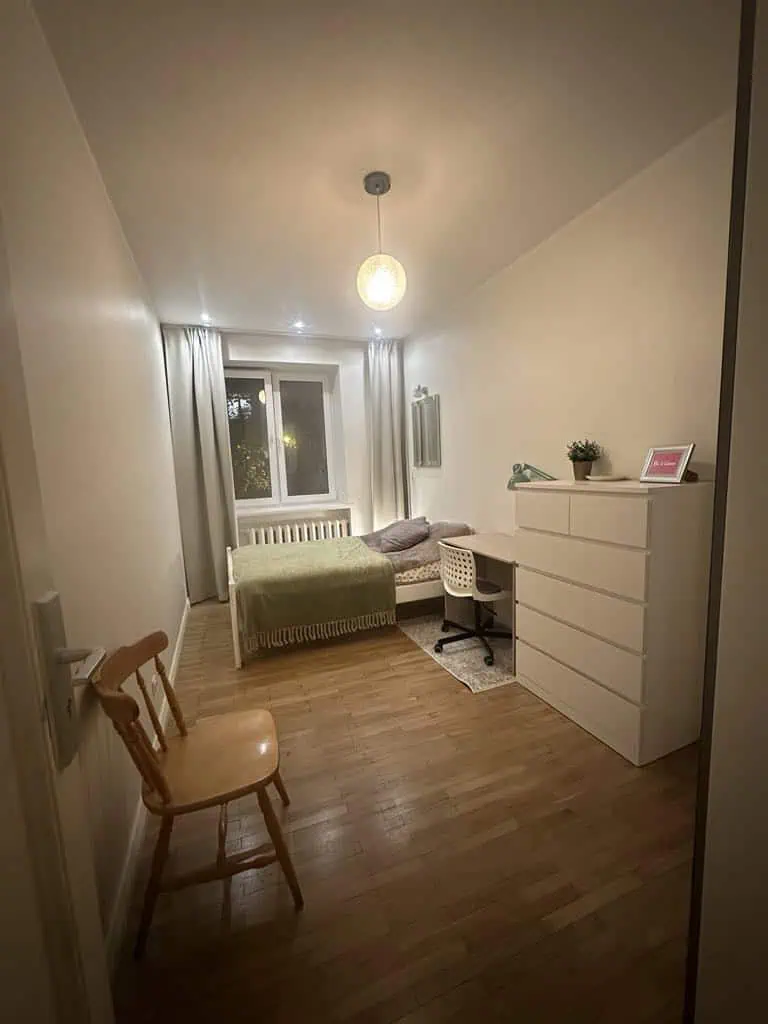 Bright, minimalistic room at Koolrooms Tallinn hostel with bed, desk, dresser, and warm lighting.