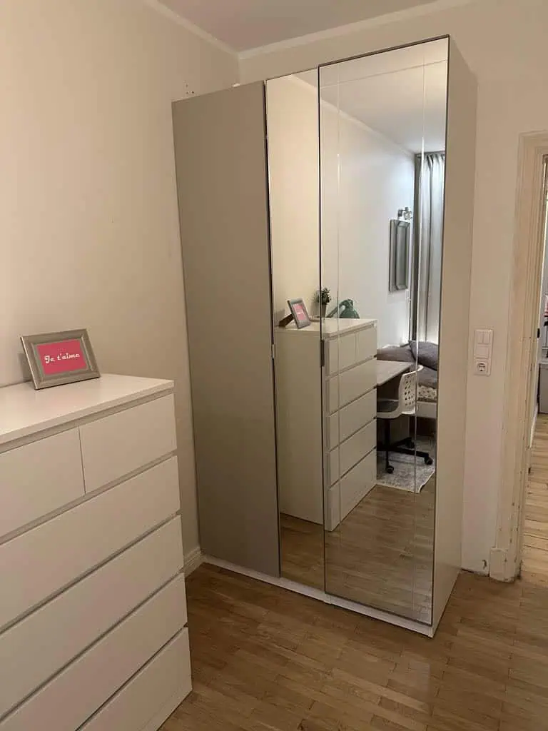 Stylish mirrored wardrobe in a cozy bedroom with wooden flooring.
