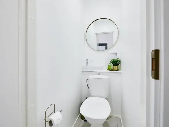 Bright, minimalist bathroom with white walls, round mirror, and small sink in Tallinn hotel.