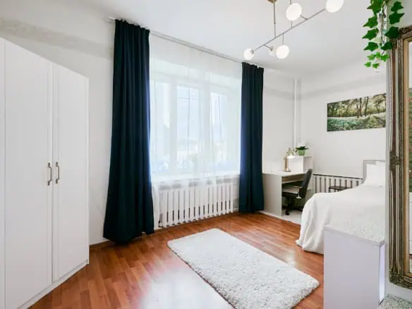 Spacious guest room with large window, white décor, and comfortable furnishings.