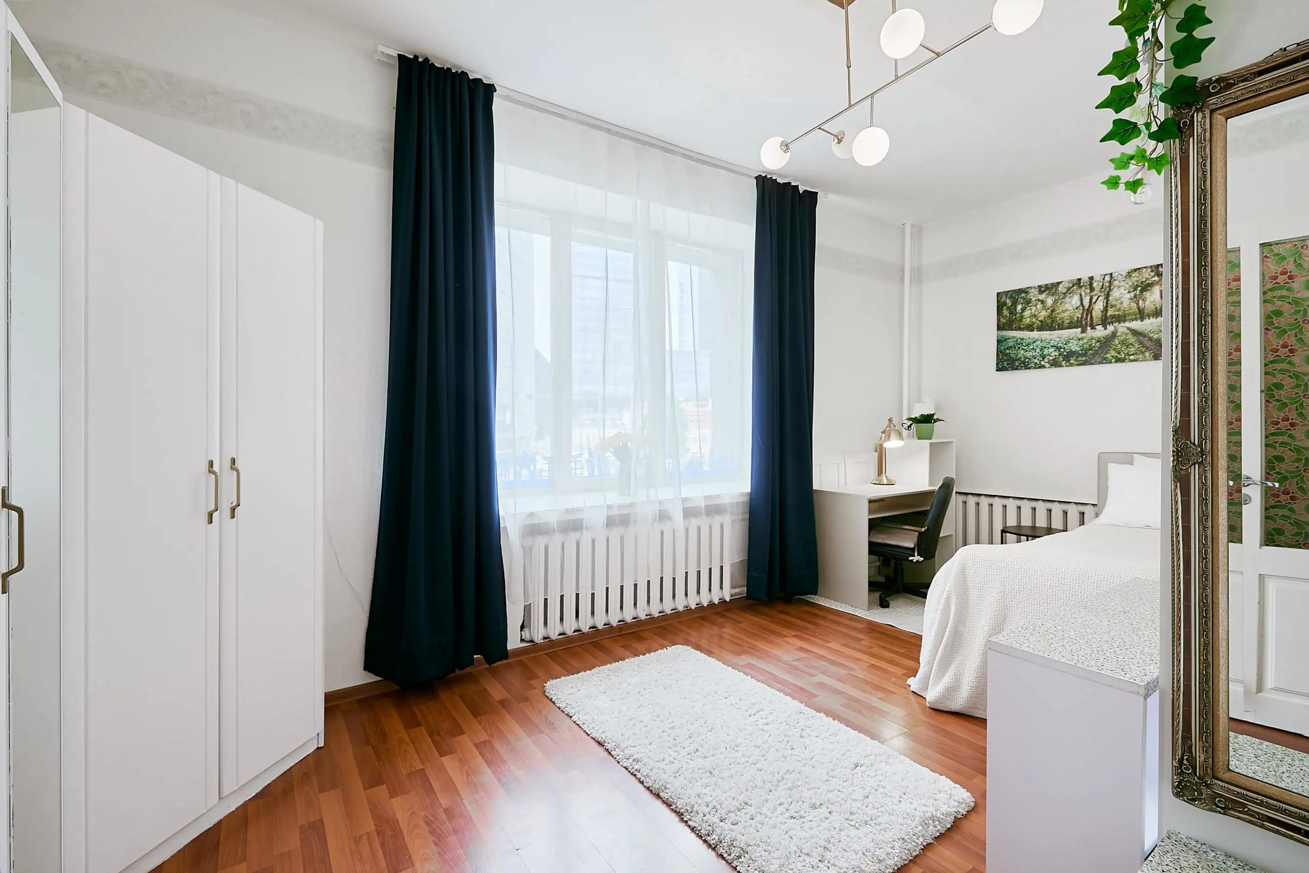 Spacious guest room with large window, white décor, and comfortable furnishings.