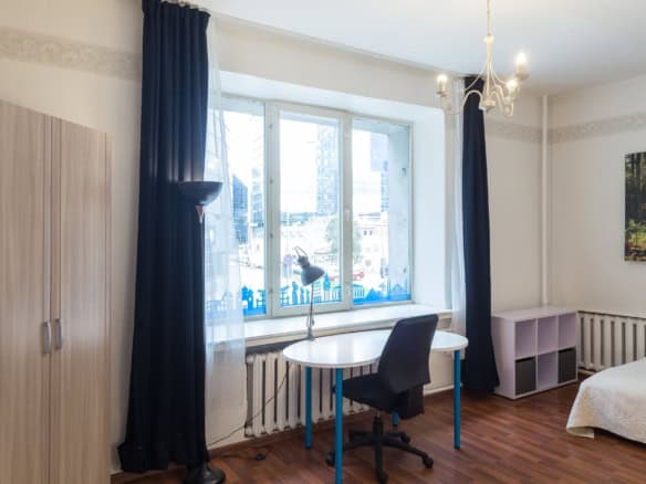 Comfy student apartment room in Tallinn with desk, large window, and city scenery for travellers.