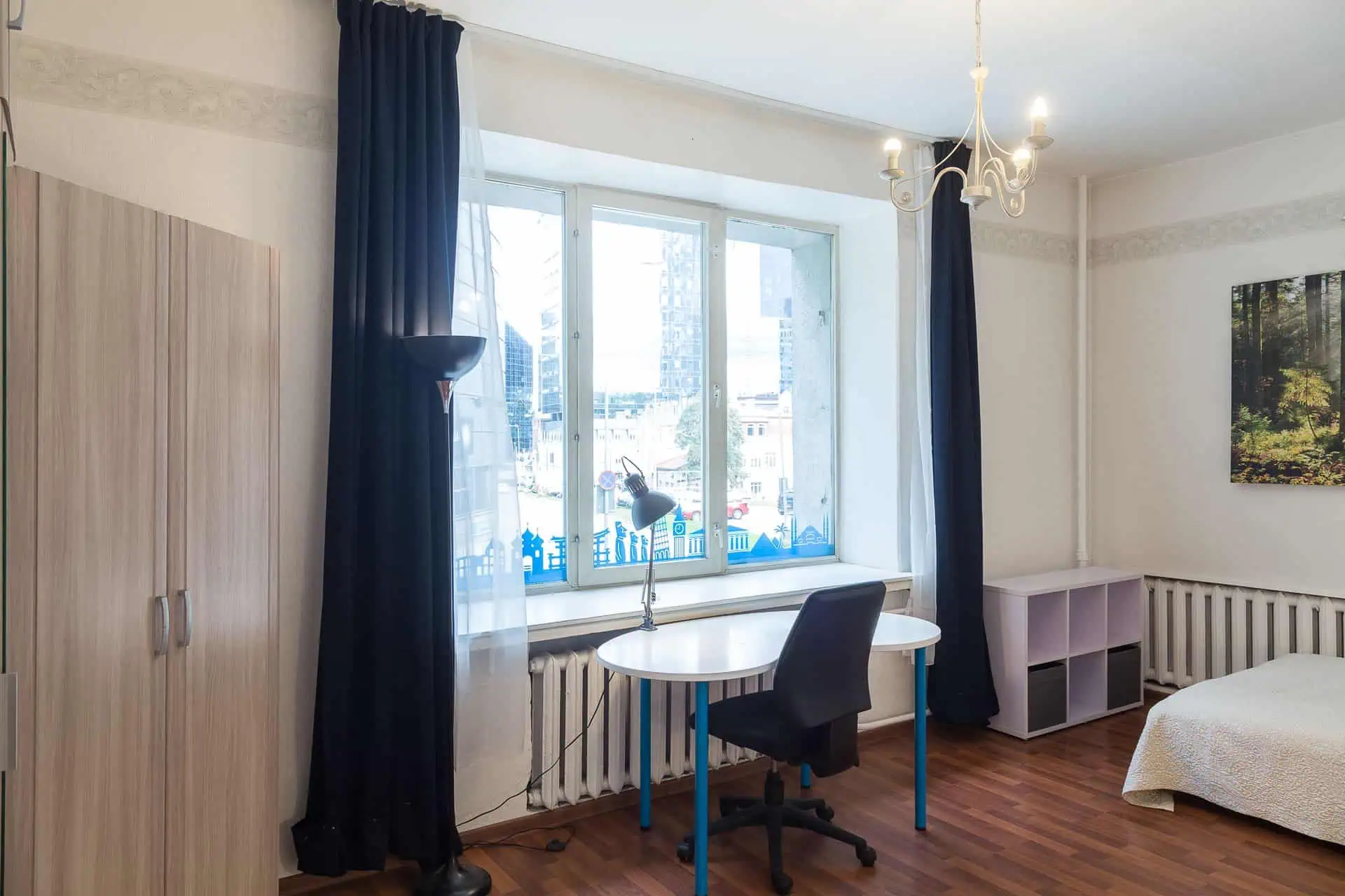 Comfy hostel room in Tallinn with desk, large window, and city scenery for travellers.