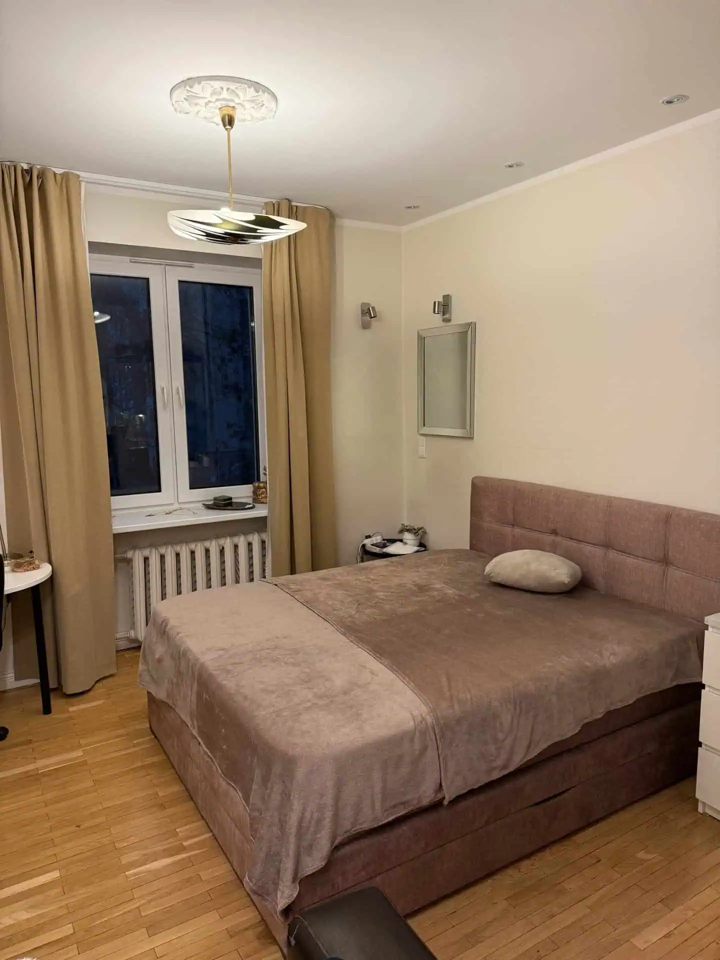 Modern bedroom with beige curtains, soft bedding, and warm lighting in Tallinn's Koolrooms Tallinn.