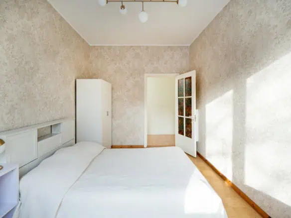 Bright hotel room at Koolrooms Tallinn with cosy white bedding and natural sunlight.