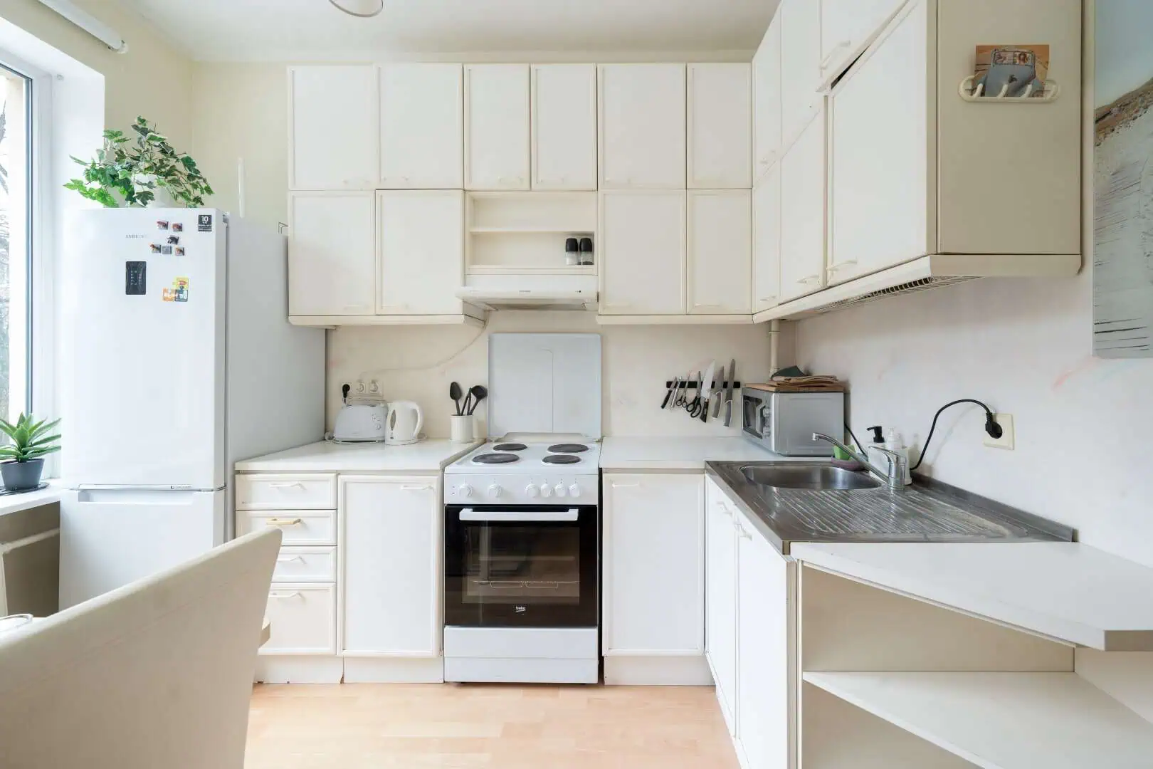 Bright white kitchen in Tallinn with modern appliances and ample storage at Koolrooms Tallinn.