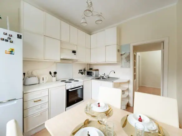 Modern kitchen at Koolrooms Tallinn with white cabinetry and dining area.