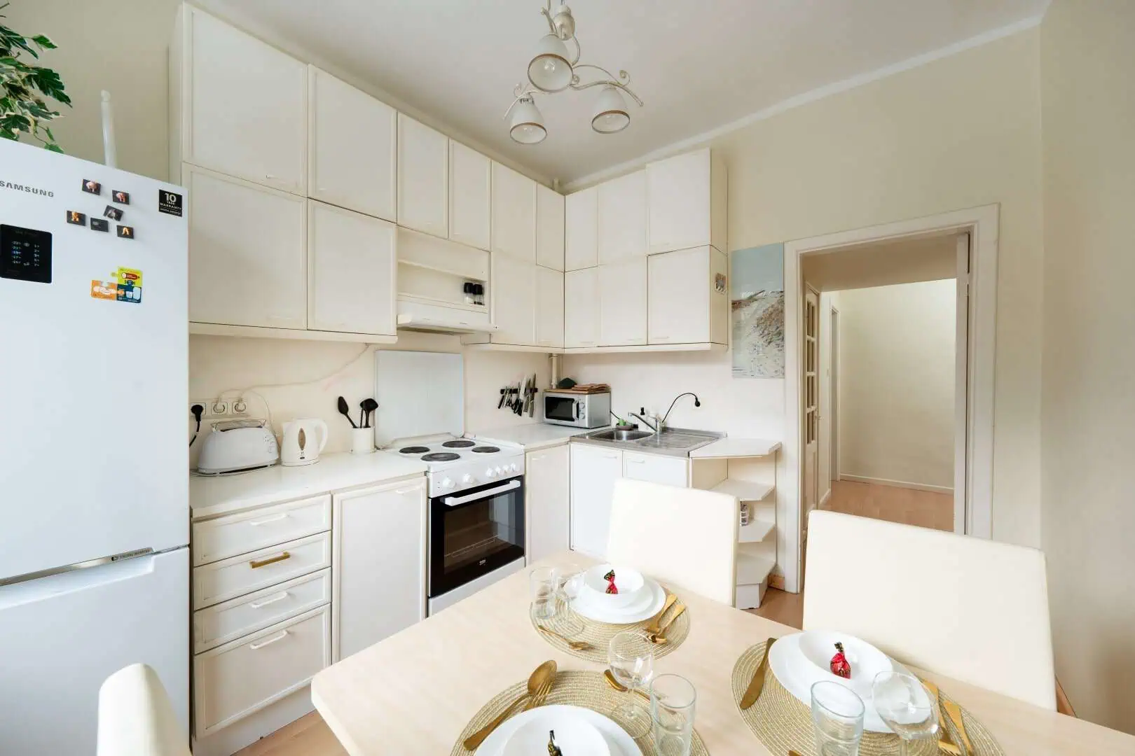 Modern kitchen at Koolrooms Tallinn with white cabinetry and dining area.