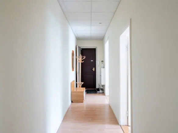 Bright corridor at Koolrooms Tallinn guesthouse with wooden bench and wall hooks.