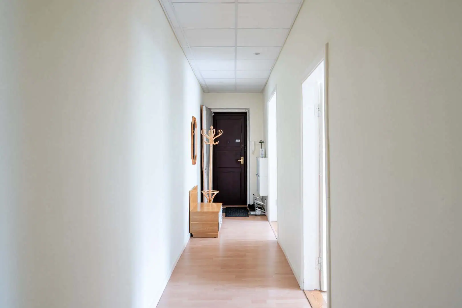 Bright corridor at Koolrooms Tallinn guesthouse with wooden bench and wall hooks.