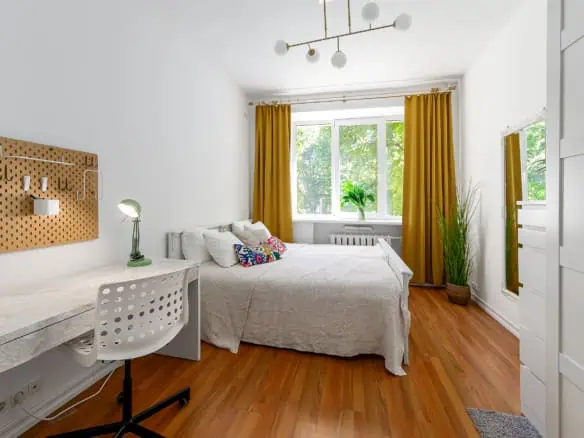 Bright, stylish Tallinn apartment bedroom with large window, warm yellow curtains, and contemporary decor, ideal for short stays.